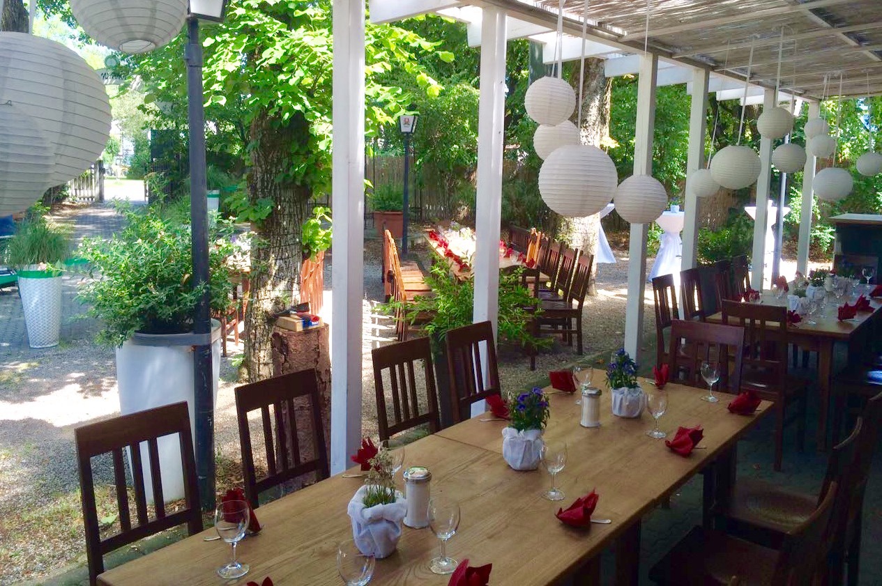 Gedeckte Tische zwischen überdachter Terrasse und Biergarten